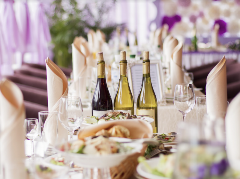Wedding table with three bottles of wine, wine glasses and food